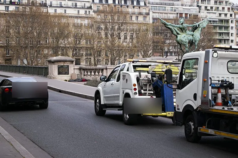 Dépanneuse pick-up et camion plateau sur un pont parisien