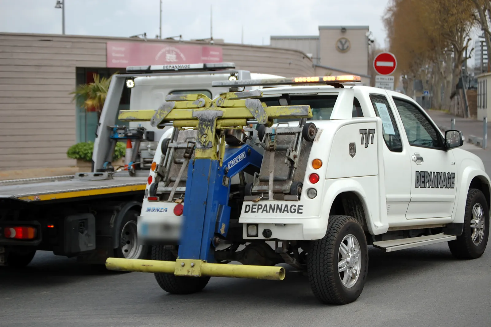 Dépanneuse Fast Depann avec bras de levage hydraulique, devant un camion plateau (photo d’illustration – dépannage pour crevaison à Clamart)