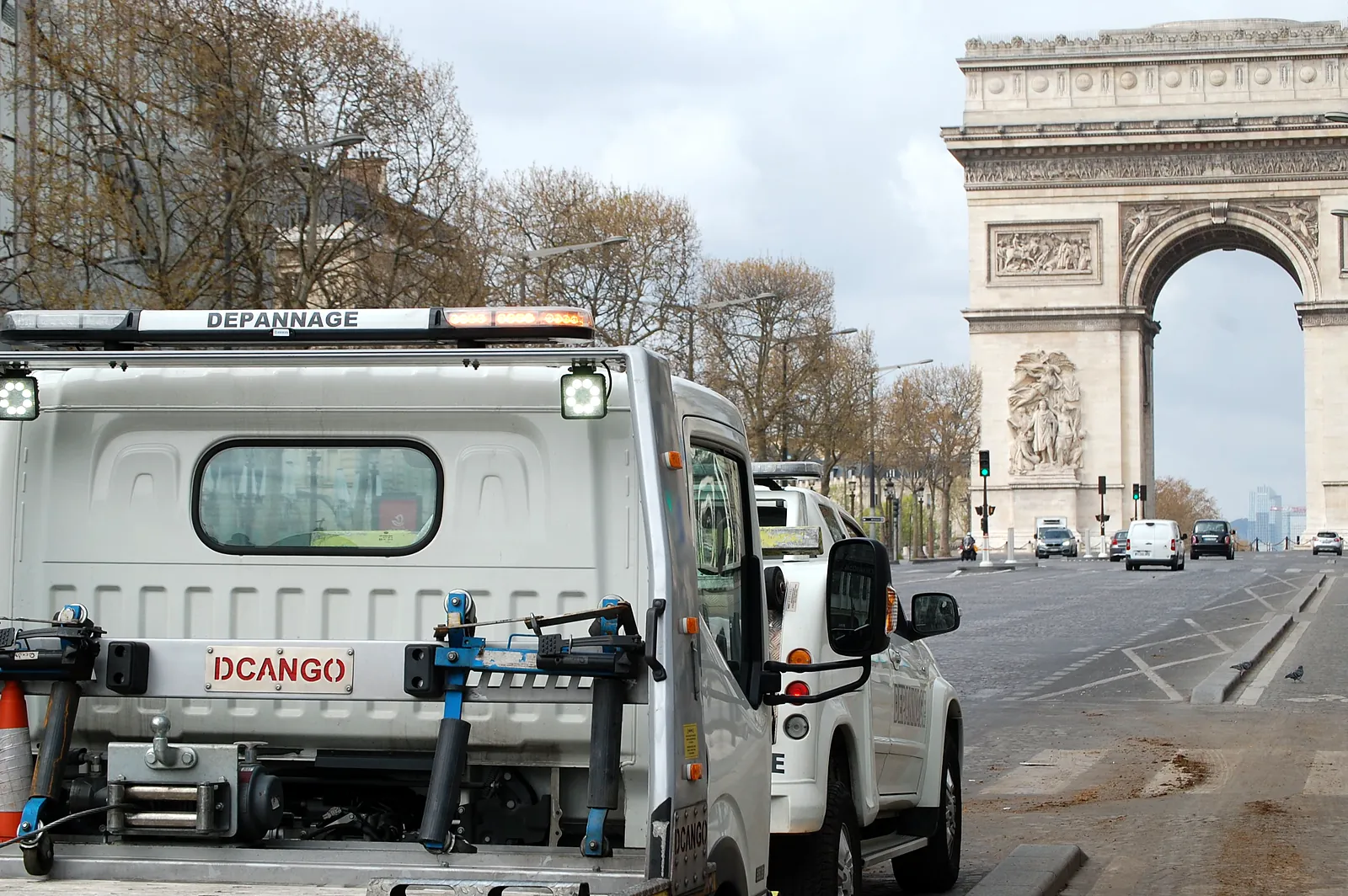 Camion plateau Fast Depann sur les Champs-Élysées, devant l’Arc de Triomphe – Remorquage à Paris