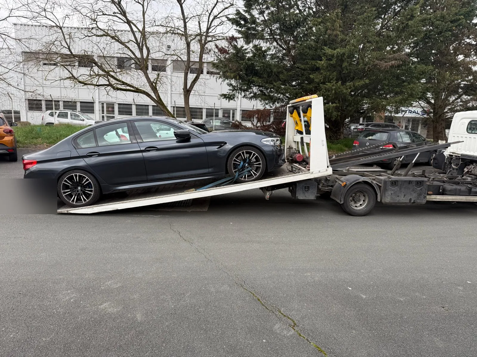 Berline grise montant sur un camion plateau dans une rue – Dépannage auto