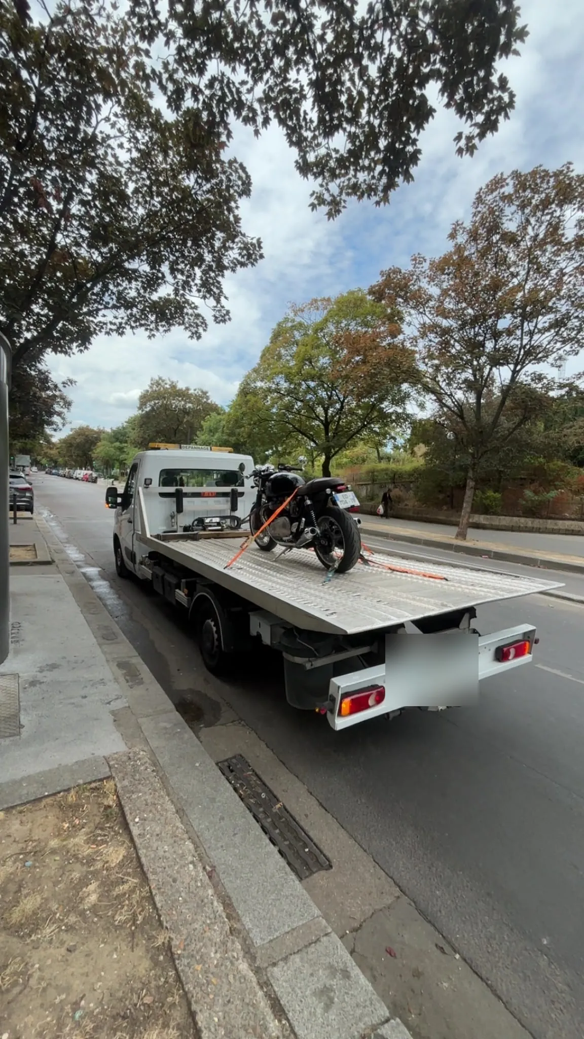 Moto transportée sur une dépanneuse plateau dans une rue arborée (photo d’illustration – à Soissons (02200))