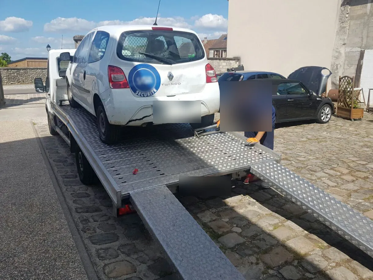 Dépanneur chargeant une Renault Twingo sur un plateau dans une cour pavée à Drancy – en Seine-Saint-Denis (93)