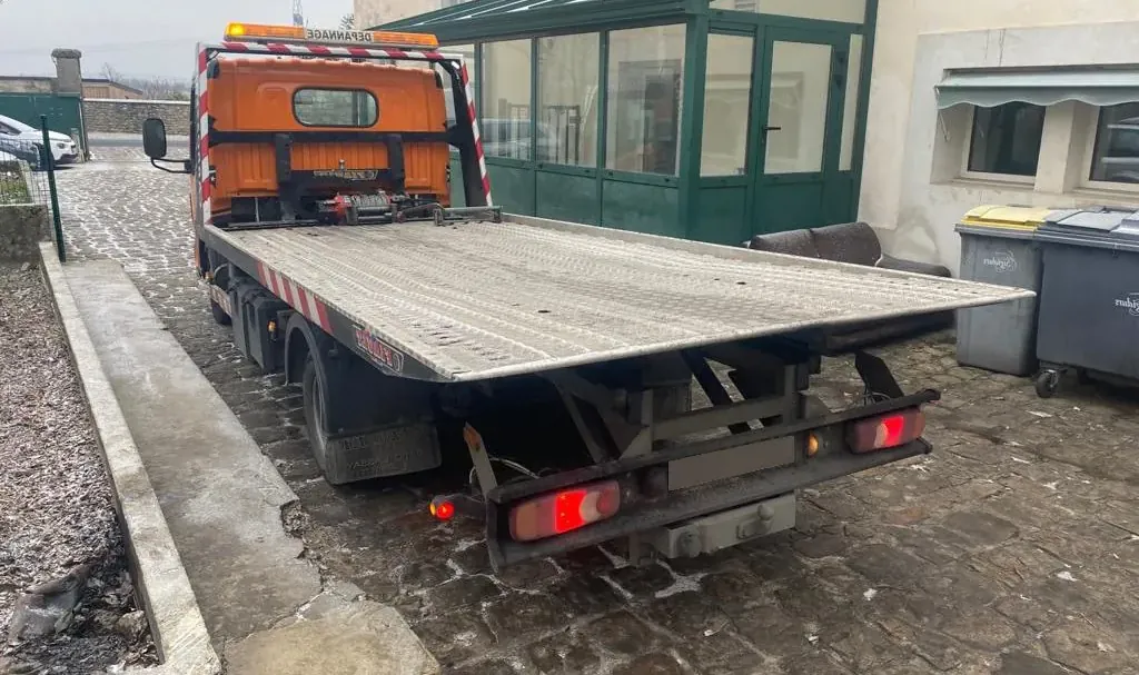 Camion plateau orange stationné dans une cour à Fontainebleau – en Seine-et-Marne (77)