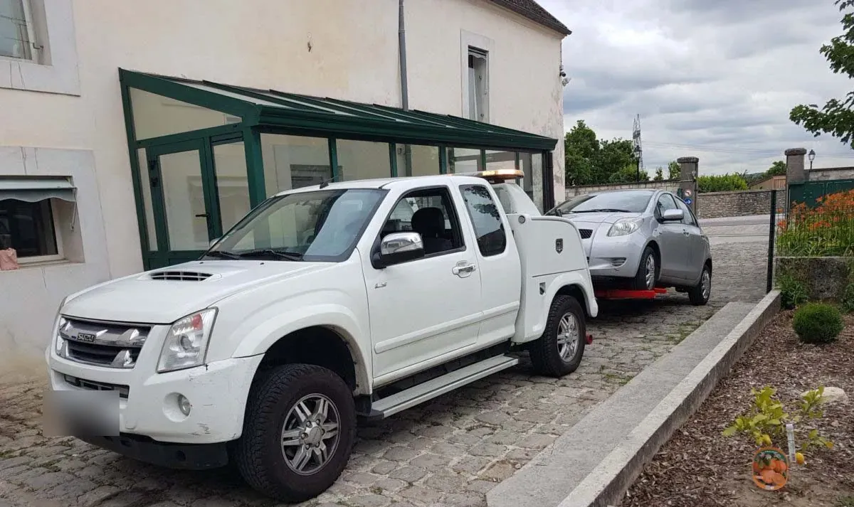 Dépanneuse pick-up Isuzu et voiture sur chariots dans une cour aux Lilas – en Seine-Saint-Denis (93)