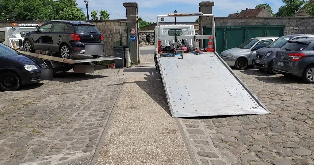 Deux camions plateaux dans une cour pavée, rampe baissée, à Meaux