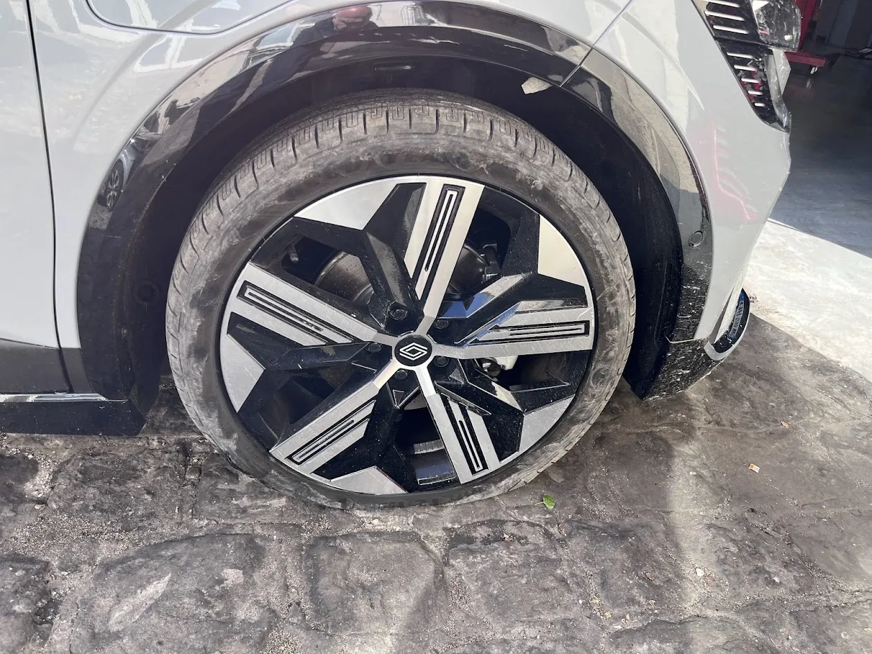 Roue avant d’une voiture blanche crevée sur un parking à Mitry-Mory